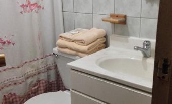 a bathroom with white tiles , towels , and a toilet next to a sink and shower at Hotel Miramar