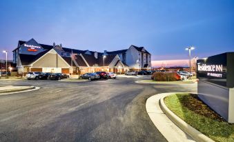 a large , well - lit parking lot with multiple cars and buildings in the background at night at Residence Inn Dayton Beavercreek