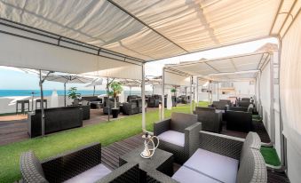 an outdoor patio area with black furniture , including a couch , chairs , and a dining table at Vik Gran Hotel Costa del Sol