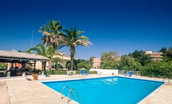 a large outdoor swimming pool surrounded by palm trees , with lounge chairs and umbrellas placed around the pool at Anita