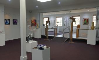 an art gallery with various paintings displayed on the walls , and a person working out in the background at Rosevears Riverview Hotel