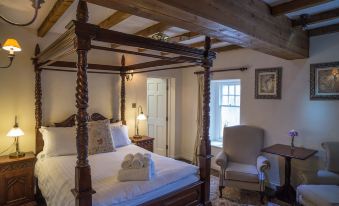 a cozy bedroom with a wooden four - poster bed in the center , surrounded by furniture and decorations at The Peak Hotel