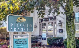 a sign for piccolo arancio restaurant is shown in front of a building with autumn leaves on the ground at The Farmington Inn and Suites
