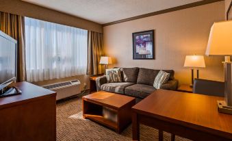 a hotel room with a large couch , two coffee tables , and a window with curtains at Best Western Plus Barclay Hotel