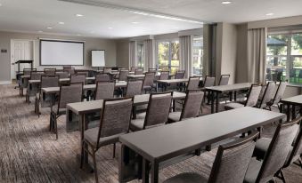 a large conference room with rows of chairs and tables , a projector screen , and windows at Residence Inn Stockton