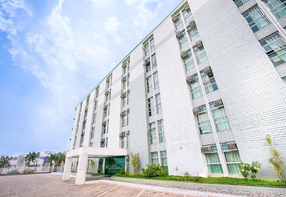 a large white building with many windows and doors , situated in a city setting with a parking lot at Verona Hplus Long Stay