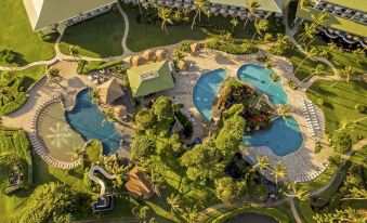 aerial view of a resort with a pool surrounded by lush greenery and palm trees at OUTRIGGER Kaua'i Beach Resort & Spa