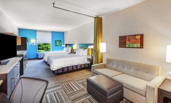 a hotel room with two beds , a couch , and a coffee table , all decorated in white and yellow colors at Home2 Suites by Hilton Gonzales