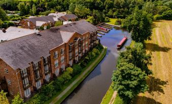 aerial view of a brick building surrounded by trees , with a river running through it at Lion Quays Resort