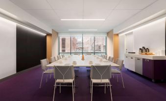 a large conference room with a long table , chairs , and a view of the city through a window at Yotel Boston
