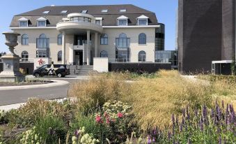 a modern building with a gray roof and large windows is surrounded by a garden of flowers at Hotel Acropolis