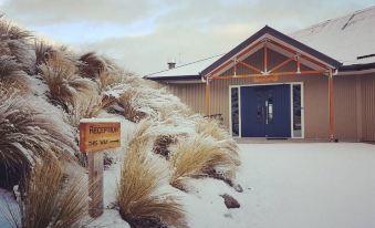a snow - covered house with a blue door and a sign in front , set against a cloudy sky at Lakestone Lodge