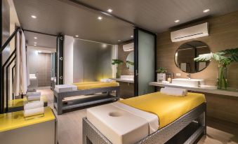 a modern spa room with two massage tables , one yellow and one white , situated in a room with multiple mirrors at Astoria Palawan