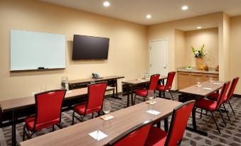 a classroom setting with desks and chairs arranged in a row , along with a television mounted on the wall at TownePlace Suites Clovis