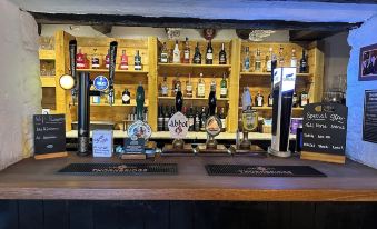 a bar with wooden shelves filled with various bottles and taps , including an order for drinks at 1 2 pm at The Bear Inn