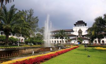 a large fountain in the middle of a park with colorful flowers and buildings in the background at High Livin Apartment Baros