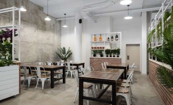 a modern restaurant with wooden tables and chairs , brick walls , and pendant lights , as well as a bar area at Rydges Mackay Suites, an EVT hotel
