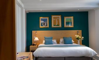 a large bed with a wooden headboard is in a room with green walls and two pictures on the wall at Royal Maritime Hotel