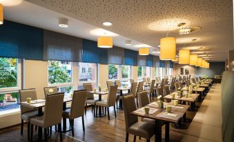a large dining room with multiple tables and chairs arranged for a group of people to enjoy a meal together at Leonardo Hotel Berlin