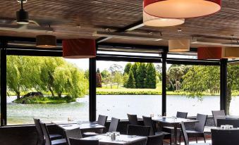 an outdoor dining area with tables and chairs , surrounded by trees and a lake view at Aspect Tamar Valley Resort