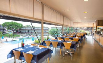 a restaurant with tables and chairs set up for diners , along with a swimming pool in the background at Aparthotel Comtat Sant Jordi