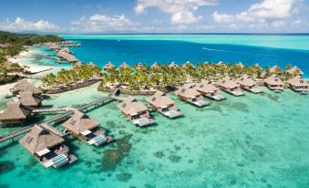 a picturesque view of a tropical island with several thatched - roof bungalows situated on stilts over the ocean at Conrad Bora Bora Nui