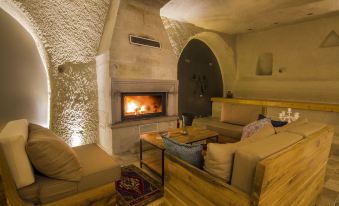 a cozy living room with a fireplace , wooden furniture , and a rug on the floor at Azure Cave Suites - Cappadocia