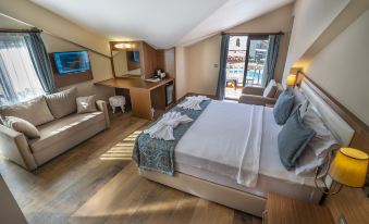 a large bed with white linens is in a room with wooden floors and a sliding glass door at Dalyan Live Spa Hotel