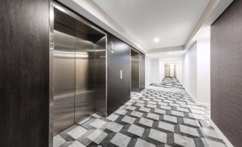 a hallway with two elevators , one on the left and one on the right , and a checkered floor at The Milton Brisbane