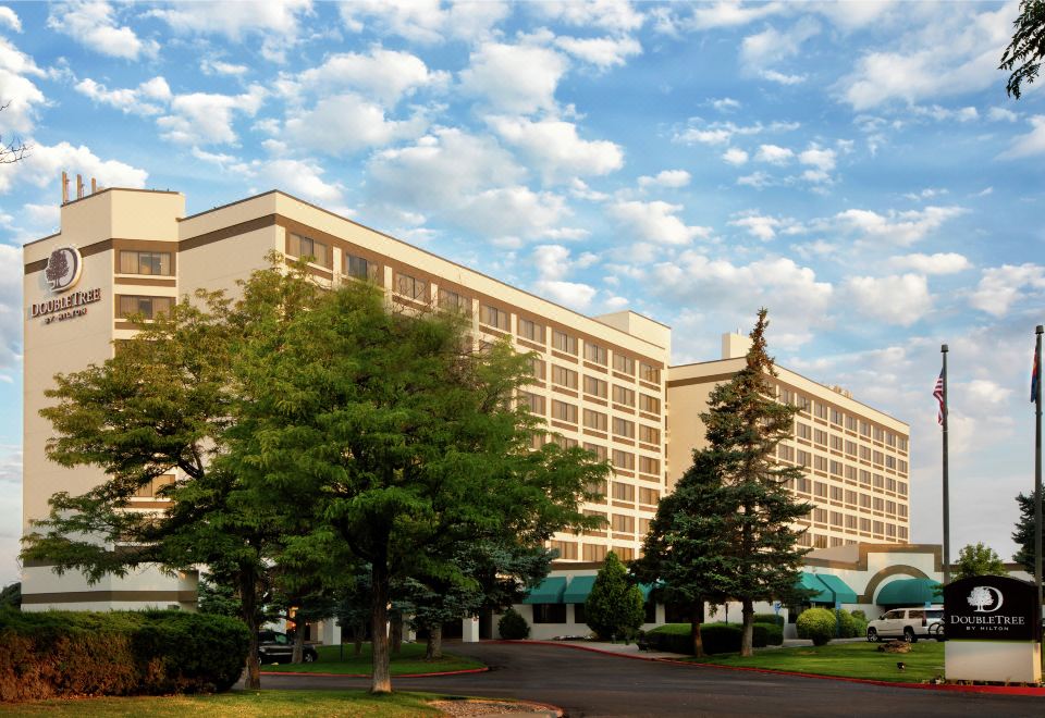 a large hotel building surrounded by trees and grass , with a blue sky in the background at DoubleTree by Hilton Hotel Grand Junction