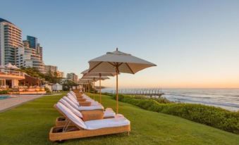 a row of sun loungers and umbrellas on a grassy hill overlooking the ocean , with a city skyline in the background at Beverly Hills