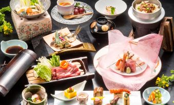 a table is filled with various types of food and drinks , including sushi , tea , and desserts at Hotel Fuji