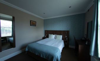 a neatly made bed with blue sheets and white pillows is in a room with a wooden headboard at The Buxted Inn