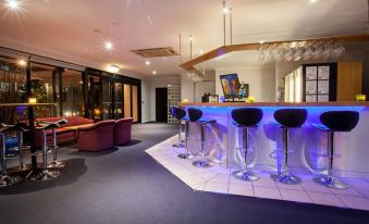 a modern hotel lobby with a bar area featuring a blue countertop and several stools at Springwood Motor Inn