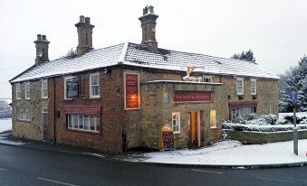 a brick building with a red sign is situated on a street with snow on the ground at The Geese and Fountain