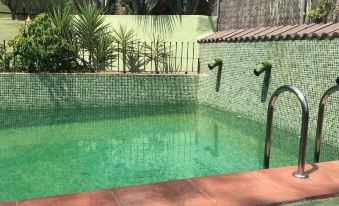 a green tiled swimming pool surrounded by a brick wall , with two faucets on either side of the pool at La Casa Verde