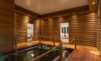 a modern , wooden interior with a central pond and wooden decking , offering a serene atmosphere at The Swan Valley Retreat