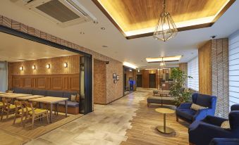 a modern hotel lobby with wooden paneling , a reception desk , and several couches arranged around a coffee table at Sotetsu Fresa Inn Kamakura-Ofuna Higashiguchi