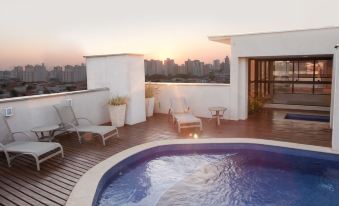 a rooftop deck with a pool , lounge chairs , and a city skyline in the background at Ibis Styles Piracicaba