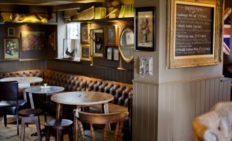 a cozy interior of a pub with wooden furniture , framed pictures on the wall , and a menu board at The White Horse