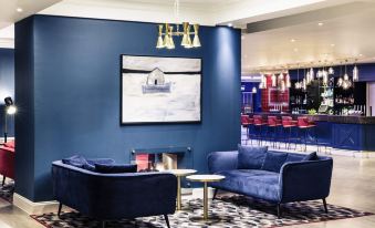 a modern living room with blue couches and chairs arranged in a seating area , creating a cozy atmosphere at Mercure Swansea Hotel