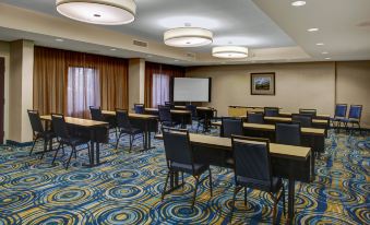 a conference room with rows of chairs arranged in a semicircle , and a projector mounted on the wall at Courtyard New Bern