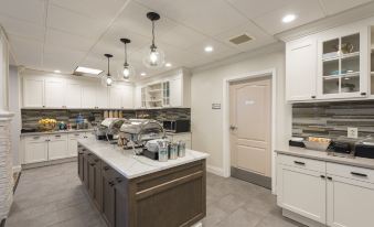 a large , well - lit kitchen with white cabinets and stainless steel appliances , including a refrigerator and a stove at Homewood Suites by Hilton Bloomington