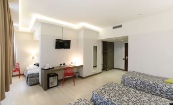 a modern hotel room with white walls , wooden floors , and black and white checkered bedspread , featuring a desk , tv , and bed at The Gate Hotel