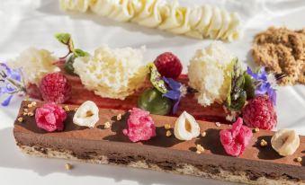 a beautifully presented chocolate dessert with raspberries and whipped cream , placed on a white plate at PARKROYAL Melbourne Airport