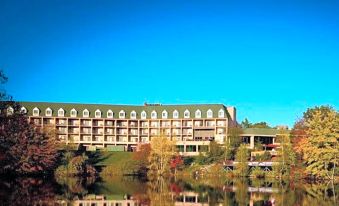 a large hotel situated on the shore of a lake , with a blue sky in the background at The Chateau Resort