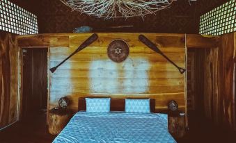 a wooden bedroom with a blue bedspread , white pillows , and two swords on the wall at Volcano House