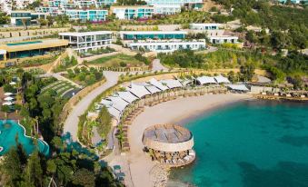 a beautiful beach resort with multiple buildings , a sandy area , and lush greenery surrounding it at Le Méridien Bodrum Beach Resort