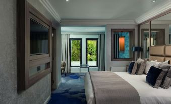 a modern bedroom with a large bed and sliding glass doors leading to an outdoor patio at Dalmeny Park House Hotel