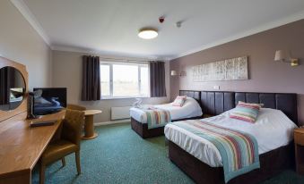 a hotel room with two beds , one on the left side of the room and the other on the right at Greetham Valley